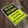 'SLOW DOWN, CHILDREN PLAYING IN THE ROAD' WARNING SIGN. TOUGH,
